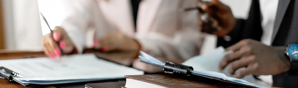 Two lawyers reviewing documents with law books on a desk. Professional legal environment.